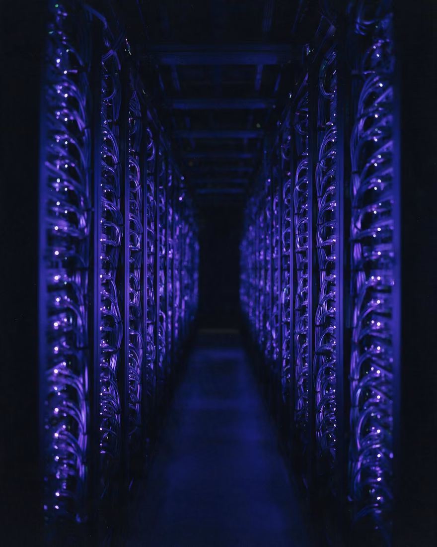 A server aisle receding into darkness, both walls edged in blue indicator light.